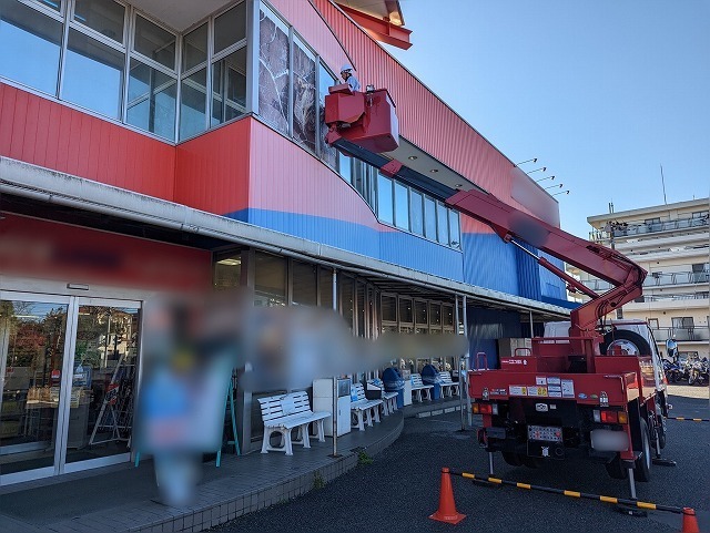 高所作業車を使用して看板シート剥がし